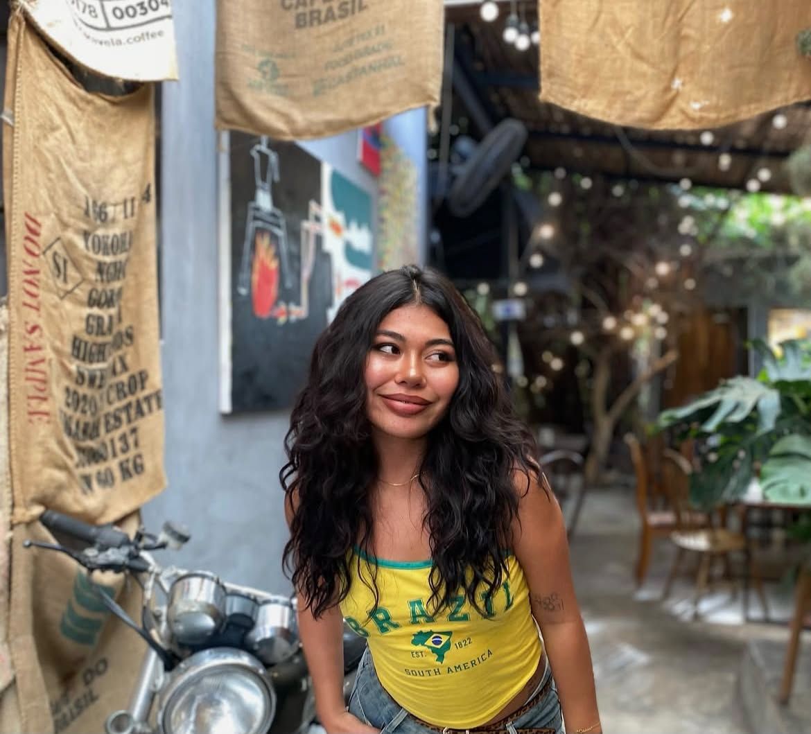 Beamy in a yellow Brazil top at a café